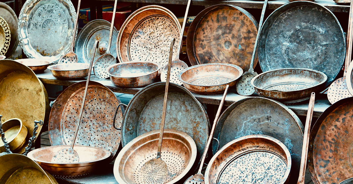 An assortment of vintage copper kitchenware displayed outdoors, showcasing rustic charm.